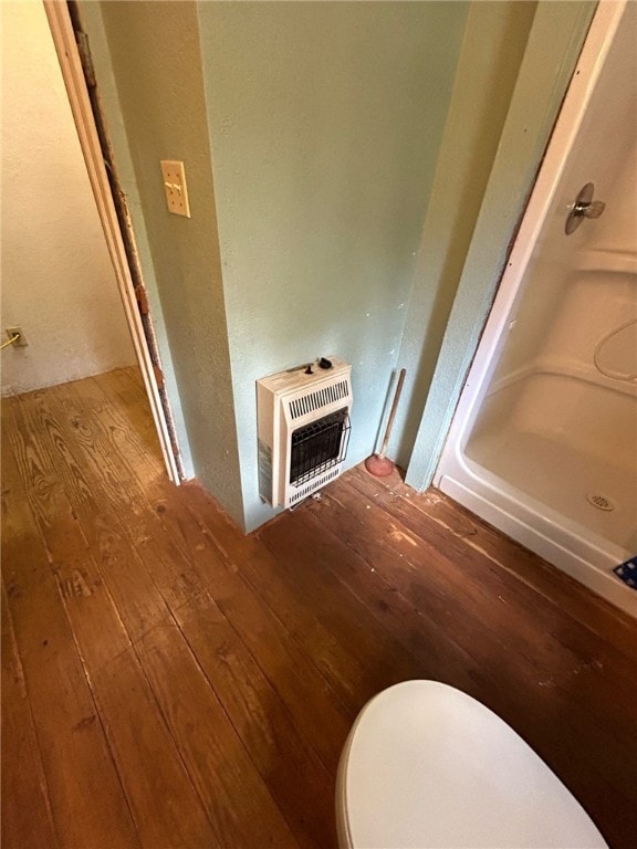 room details with heating unit, hardwood / wood-style floors, and toilet