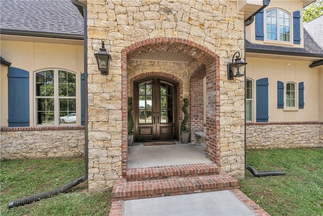 doorway to property featuring roof with shingles, french doors, stone siding, and stucco siding