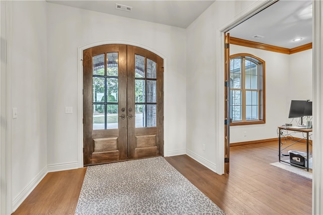 foyer entrance featuring french doors, hardwood / wood-style flooring, and crown molding