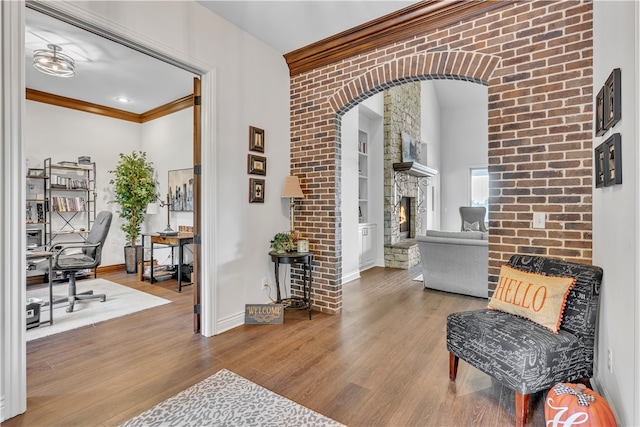 interior space featuring hardwood / wood-style floors, a stone fireplace, crown molding, and brick wall