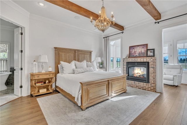 bedroom featuring a notable chandelier, a brick fireplace, beamed ceiling, and wood finished floors
