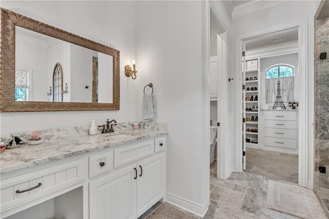 bathroom featuring crown molding, tiled shower, vanity, and baseboards
