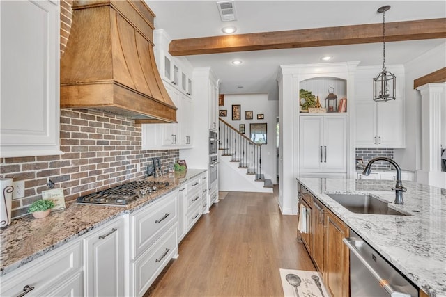 kitchen featuring custom range hood, visible vents, beamed ceiling, appliances with stainless steel finishes, and a sink