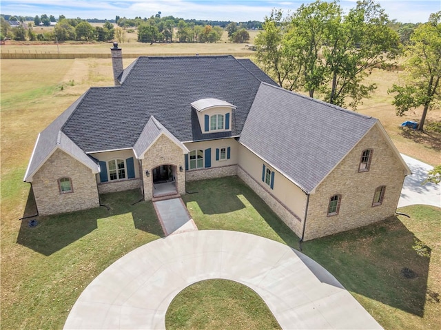 view of front of home with stucco siding, stone siding, a chimney, and a front lawn