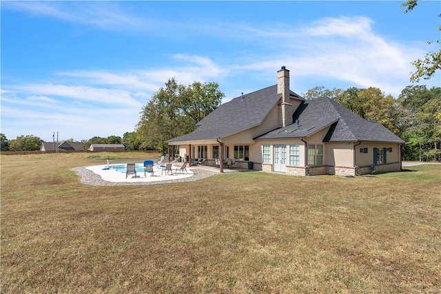 rear view of property featuring a patio area, stucco siding, a lawn, and a chimney
