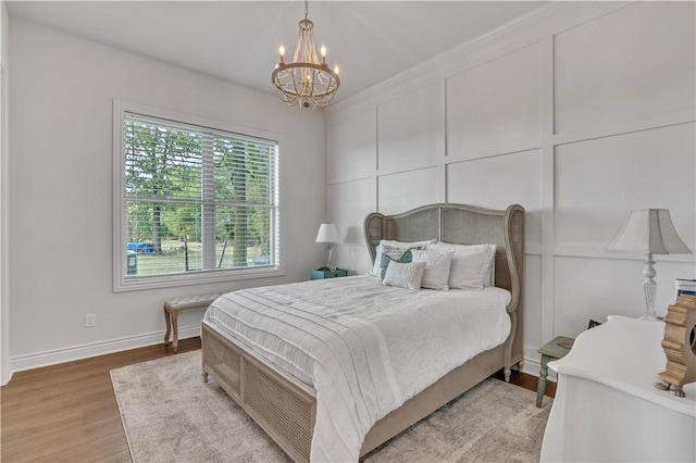 bedroom with light wood-style flooring, a notable chandelier, and baseboards