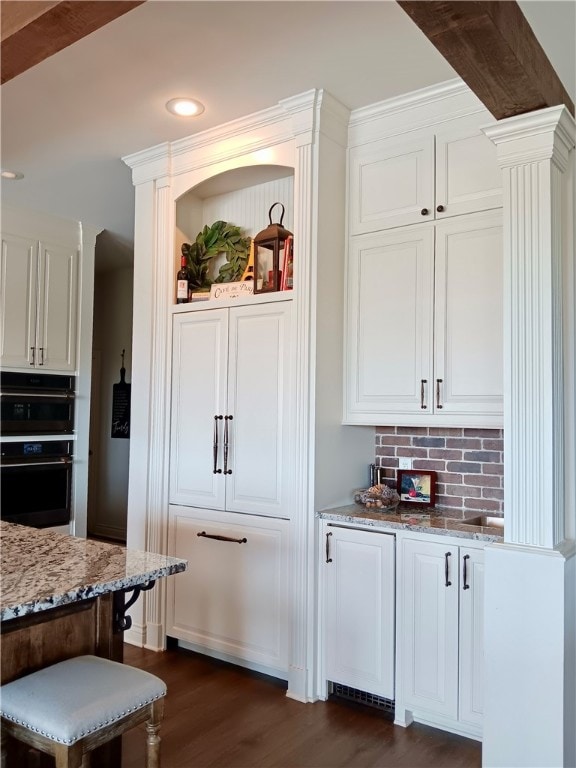 interior space featuring white cabinetry, tasteful backsplash, light stone counters, and dark hardwood / wood-style flooring