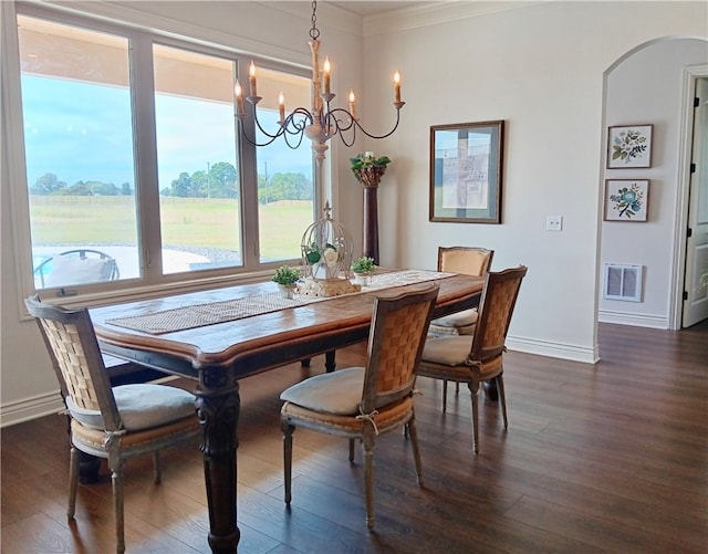 dining area featuring ornamental molding, dark wood-type flooring, and a notable chandelier