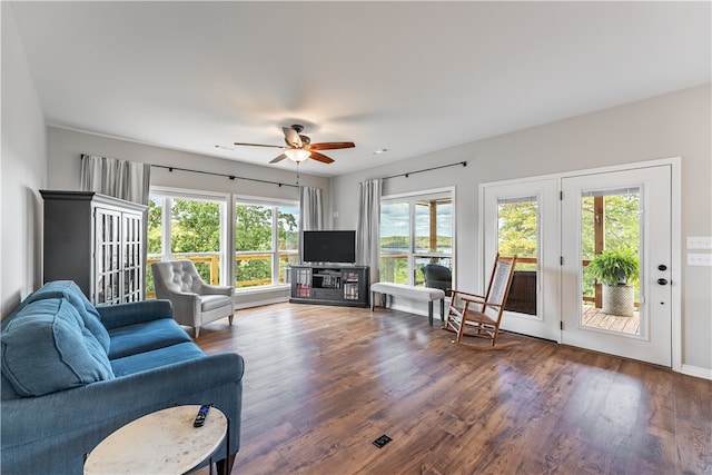 living room featuring ceiling fan, plenty of natural light, and dark wood-type flooring