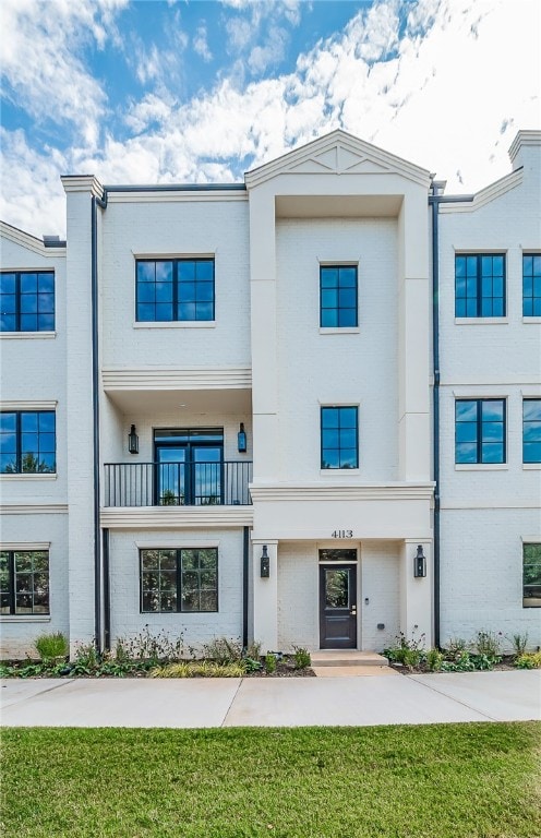 view of front of home with a balcony and a front lawn