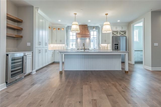 kitchen featuring light hardwood / wood-style flooring, beverage cooler, pendant lighting, and white cabinets