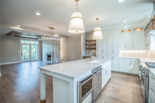 kitchen featuring white cabinets, an island with sink, pendant lighting, and sink