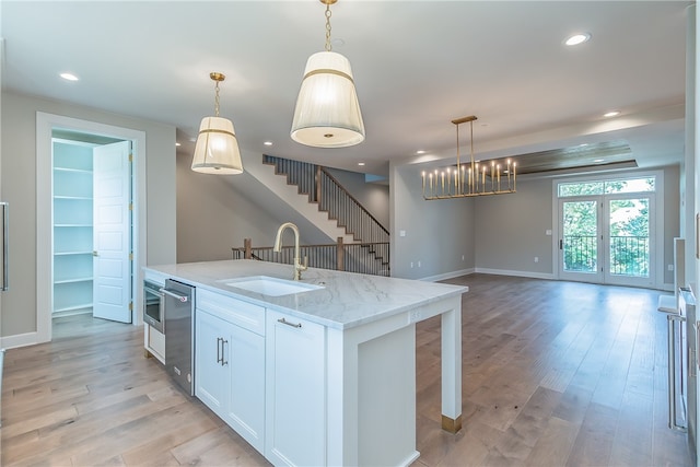 kitchen with light stone countertops, sink, pendant lighting, and white cabinets