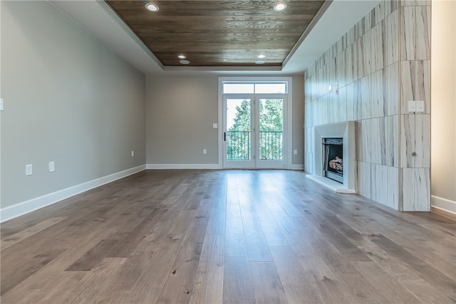 unfurnished living room with light wood-type flooring and a tray ceiling