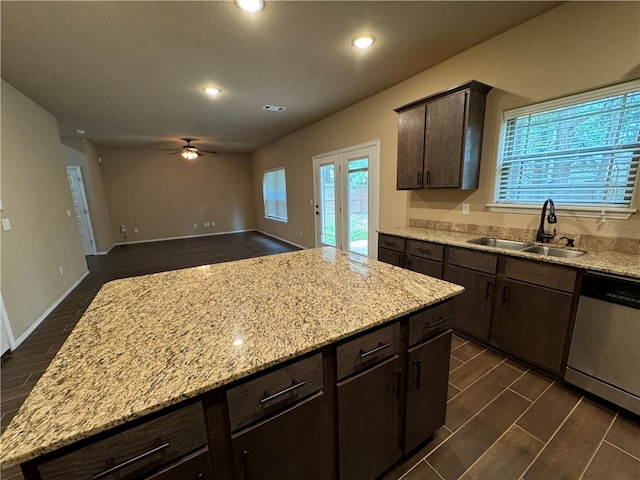 kitchen featuring dishwasher, light stone counters, plenty of natural light, and sink