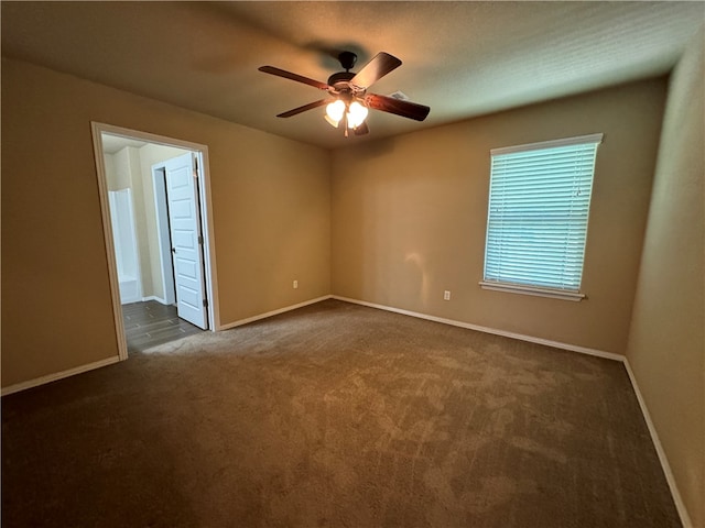 unfurnished room with dark carpet and ceiling fan