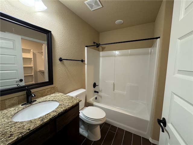 full bathroom featuring a textured ceiling,  shower combination, vanity, and toilet