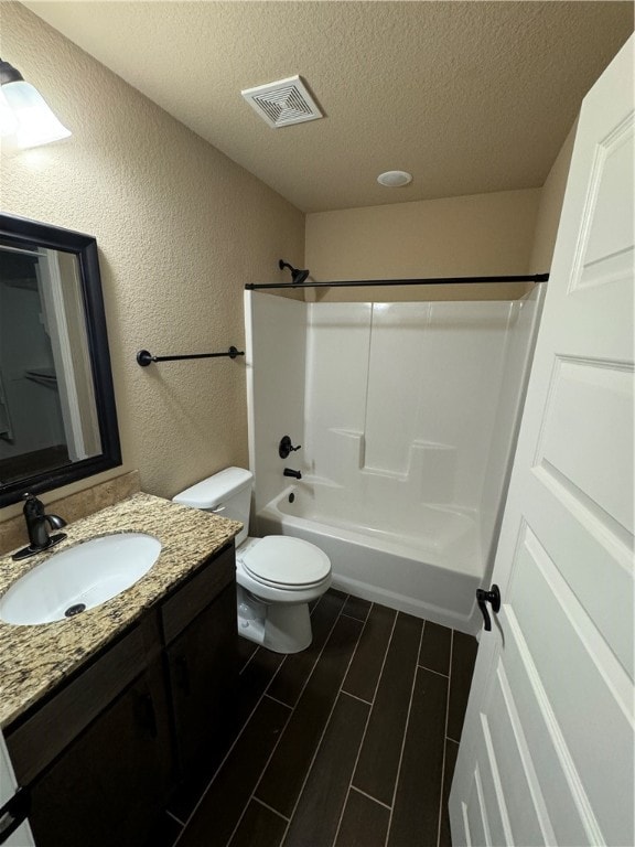 full bathroom with vanity, tub / shower combination, wood-type flooring, a textured ceiling, and toilet