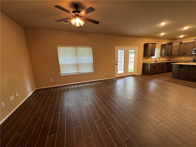 unfurnished living room with ceiling fan, sink, and dark wood-type flooring