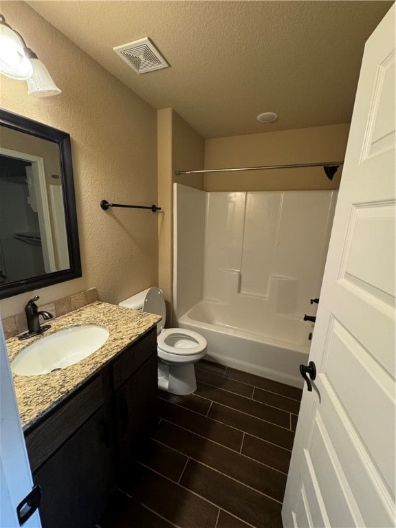 full bathroom with a textured ceiling, shower / tub combination, vanity, and toilet