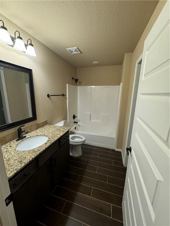 full bathroom with tub / shower combination, vanity, toilet, and a textured ceiling