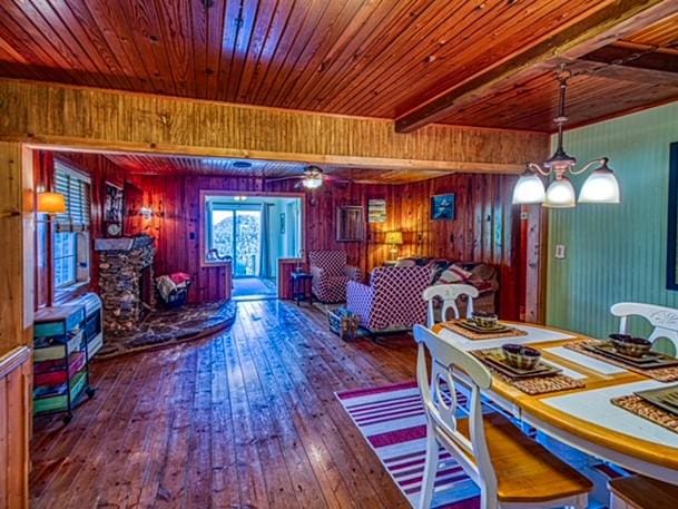 dining area featuring an inviting chandelier, wooden walls, hardwood / wood-style flooring, beam ceiling, and wood ceiling