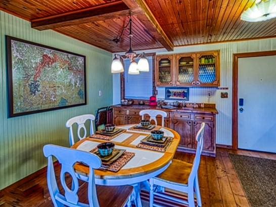 dining room with dark hardwood / wood-style floors, beam ceiling, wood ceiling, and an inviting chandelier