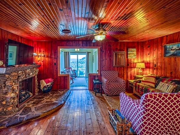 living room with a stone fireplace, wood walls, wooden ceiling, and hardwood / wood-style flooring