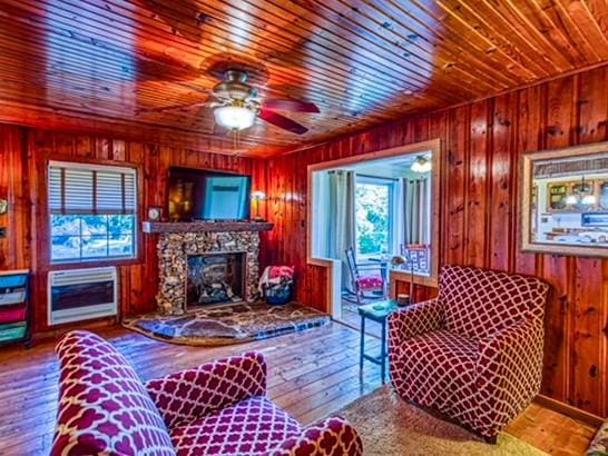 living room featuring hardwood / wood-style floors, wood walls, a stone fireplace, and wooden ceiling