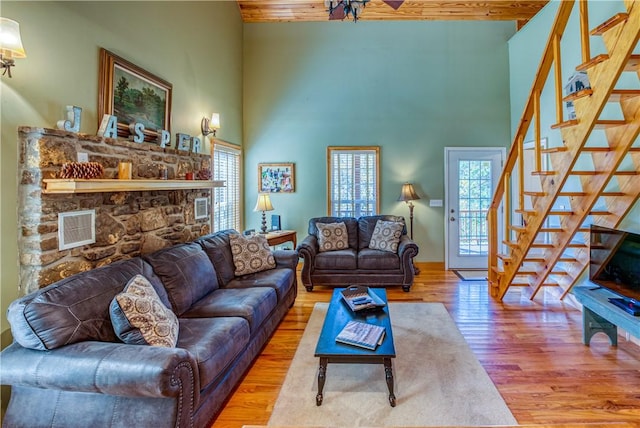 living room featuring beam ceiling, a towering ceiling, and light wood-type flooring