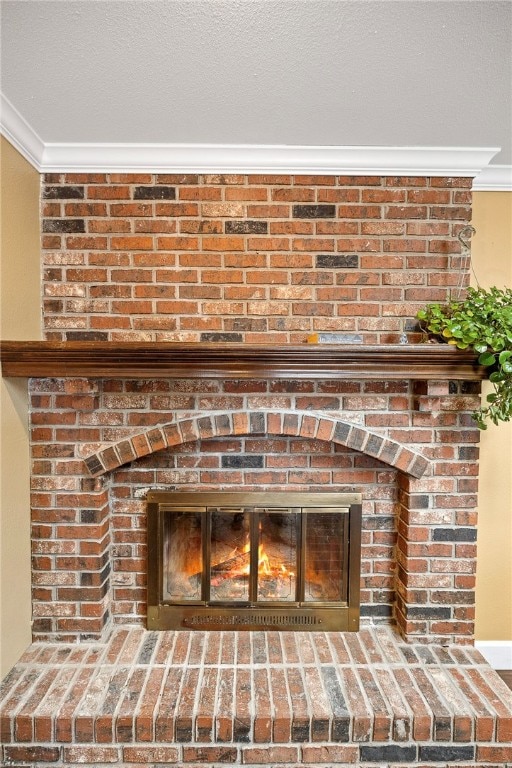 details featuring a textured ceiling, ornamental molding, and a brick fireplace