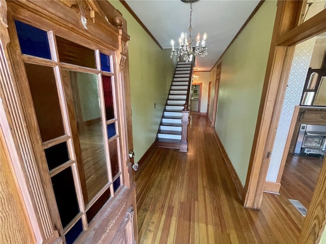 hall featuring hardwood / wood-style floors, an inviting chandelier, and ornamental molding