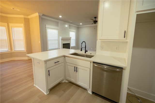 kitchen with sink, kitchen peninsula, stainless steel dishwasher, white cabinetry, and light wood-type flooring