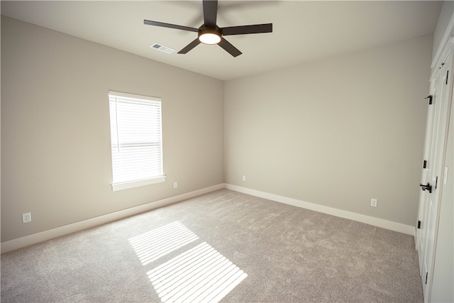 spare room with ceiling fan and light colored carpet