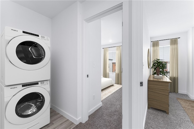 clothes washing area featuring stacked washer and dryer and light carpet