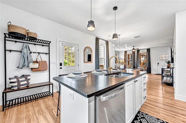 kitchen featuring sink, white cabinets, hanging light fixtures, a kitchen island with sink, and stainless steel dishwasher