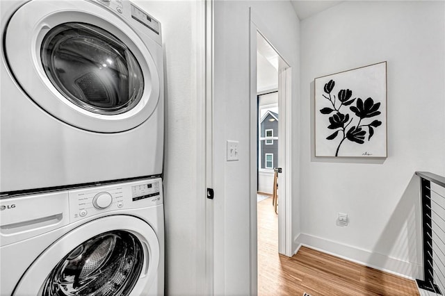 clothes washing area with stacked washer / drying machine and light hardwood / wood-style flooring