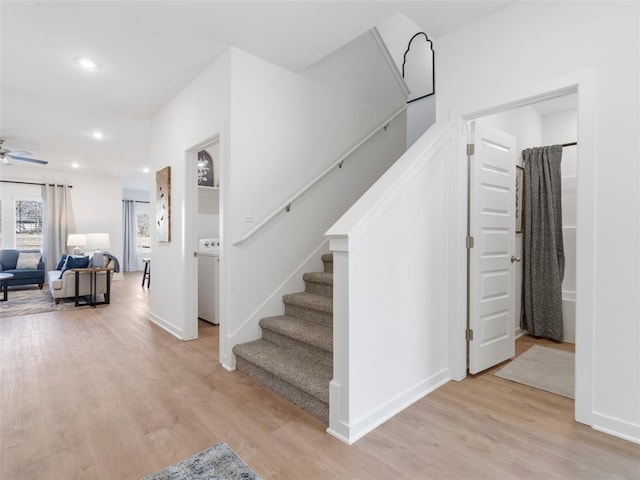 stairway with washer / dryer, hardwood / wood-style floors, and ceiling fan