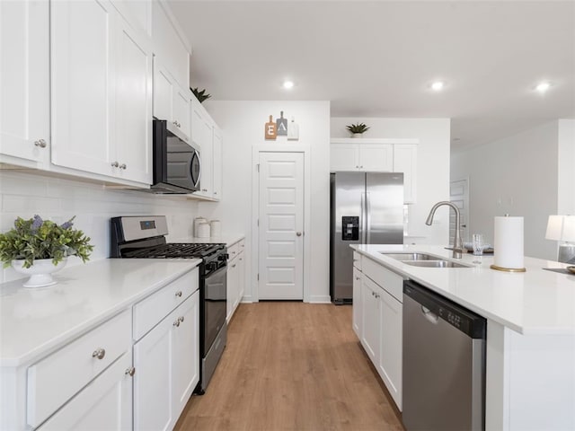 kitchen featuring sink, a kitchen island with sink, stainless steel appliances, tasteful backsplash, and white cabinets