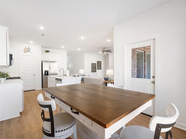 dining area featuring sink, light hardwood / wood-style floors, and ceiling fan