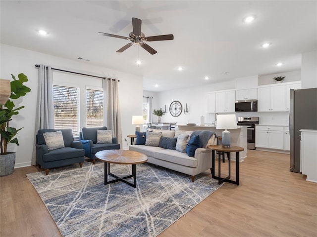 living room with ceiling fan and light wood-type flooring