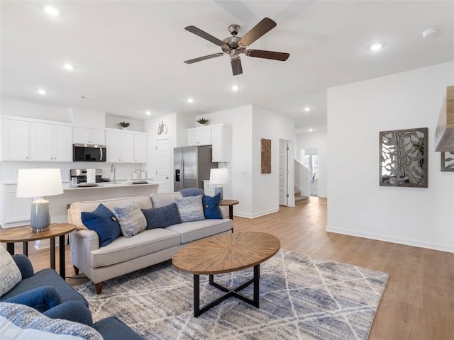 living room with ceiling fan, sink, and light hardwood / wood-style floors