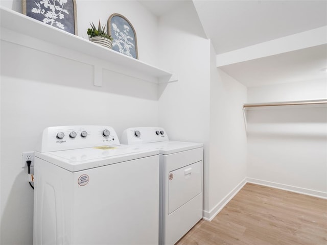 clothes washing area featuring separate washer and dryer and light hardwood / wood-style flooring