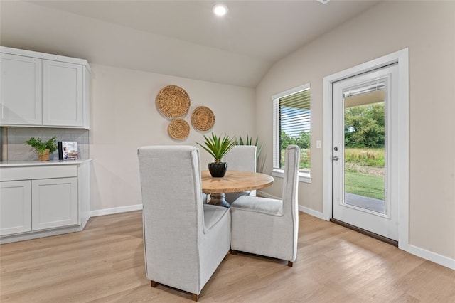 dining area with light wood-type flooring and vaulted ceiling