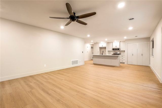 unfurnished living room featuring ceiling fan, light hardwood / wood-style flooring, and sink