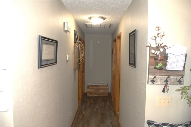 hallway with a textured ceiling and dark hardwood / wood-style flooring