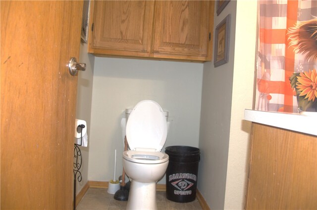 bathroom with tile patterned flooring, toilet, and curtained shower