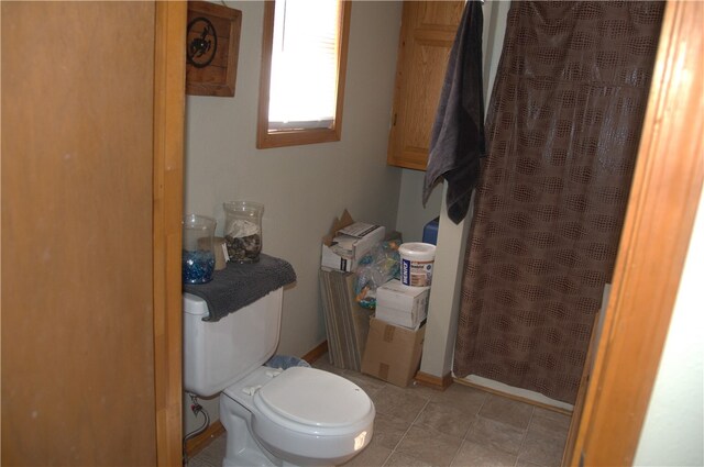 bathroom featuring a shower with shower curtain, toilet, and tile patterned floors