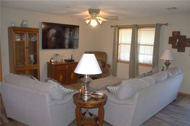 living room featuring ceiling fan, a textured ceiling, and hardwood / wood-style floors