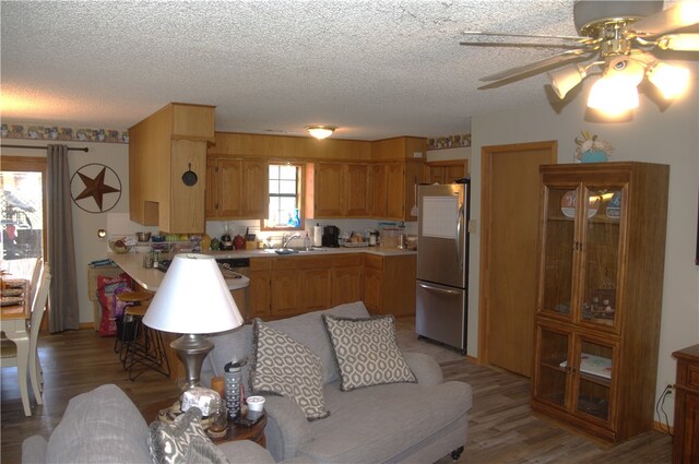 kitchen featuring a textured ceiling, sink, stainless steel refrigerator, light hardwood / wood-style flooring, and ceiling fan